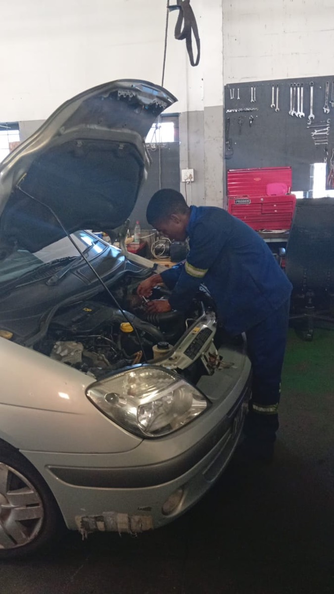 An RRC mechanic working under the bonnet of a silver Renault